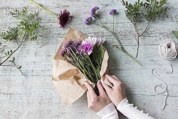 Hände einer Frau wickeln Blumenstrauss ein