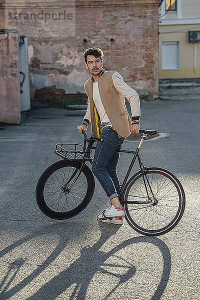 Junger Mann mit Pendler-Fixie-Fahrrad auf einem Hinterhof in der Stadt