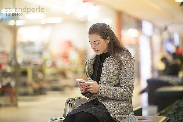Junge Frau benutzt Smartphone im Geschäft