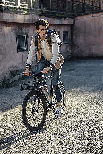 Junger Mann mit Rucksack fährt Pendler-Fixie-Fahrrad in der Stadt