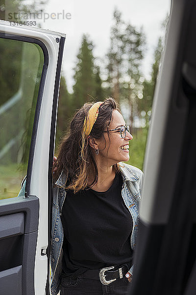 Finnland  Lappland  glückliche junge Frau an einem Auto in ländlicher Landschaft