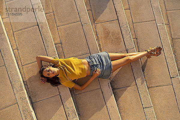 Junge Frau liegt auf Stufen im Freien