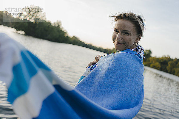 Porträt einer lächelnden  in ein Handtuch gehüllten Frau an einem See