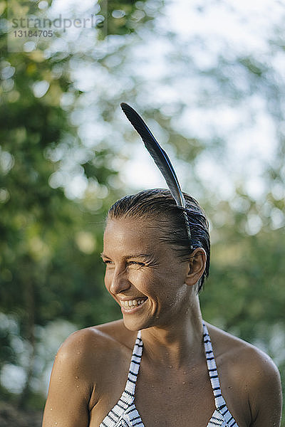 Bildnis einer glücklichen Frau mit nassem Haar  die eine Feder im Haar trägt