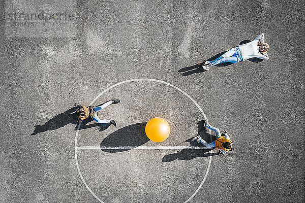 Österreich  Luftaufnahme  Blick auf Basketballfeld mit großem Ball  Mutter am Boden liegend  Kinder sitzend