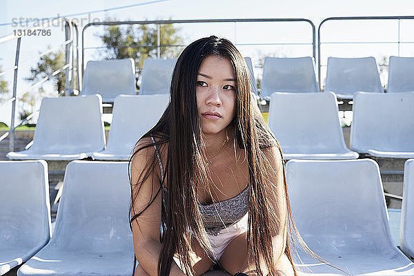 Porträt einer jungen Frau  die auf der Tribüne eines Stadions sitzt