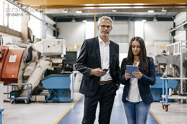 Geschäftsmann und Frau in einem High-Tech-Unternehmen  die sich in einer Fabrikhalle treffen