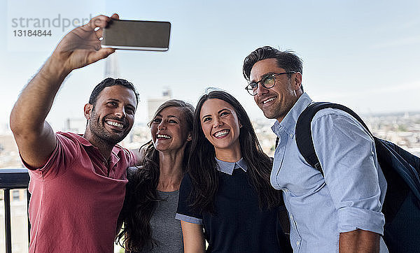 Großbritannien  London  vier Freunde  die ein Selfie mit der Stadt im Hintergrund