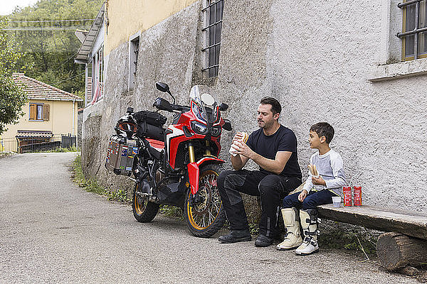 Vater und Sohn machen während einer Motorradtour eine Mittagspause