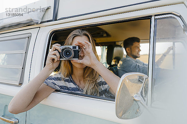Frau fotografiert aus dem Fenster eines Wohnmobils mit fahrendem Mann