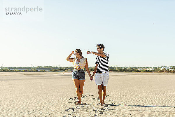 Junges Paar geht Hand in Hand am Strand
