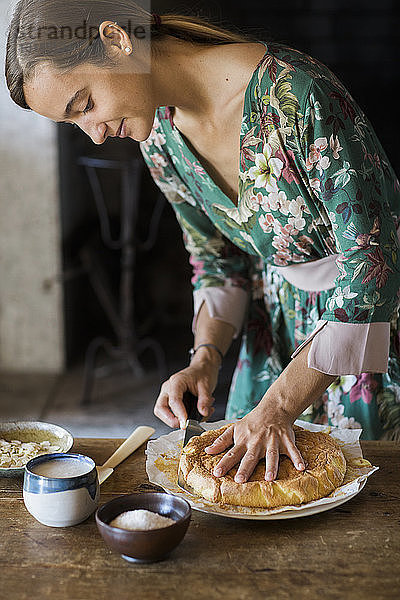Junge Frau schneidet selbstgebackenen Kuchen an