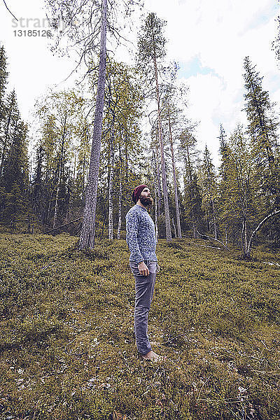 Schweden  Lappland  Mann steht auf Waldlichtung und entspannt