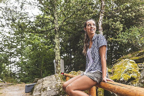 Italien  Massa  lächelnde junge Frau sitzt auf einem Holzzaun in den Alpi Apuane