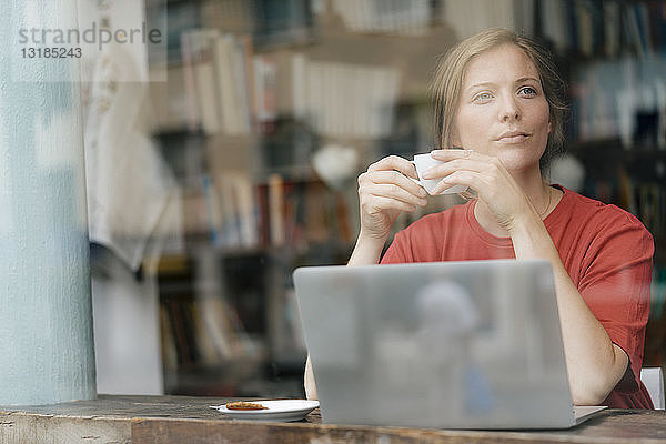 Junge Frau mit Tasse Kaffee und Laptop in einem Cafe