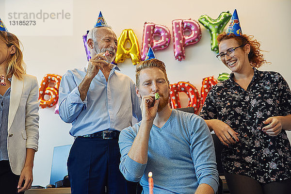 Kollegen feiern Geburtstag im Amt mit Partyblower und Partyhüten