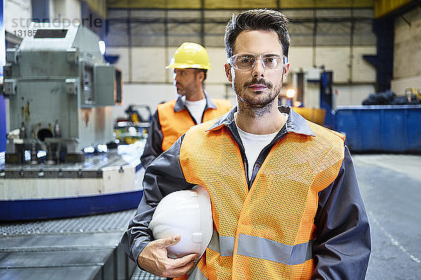 Porträt eines seriösen Mannes mit Arbeitsschutzkleidung in einer Fabrik