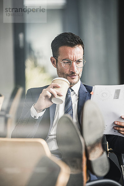 Geschäftsmann liest Dokumente während seines Kaffeeklatsches