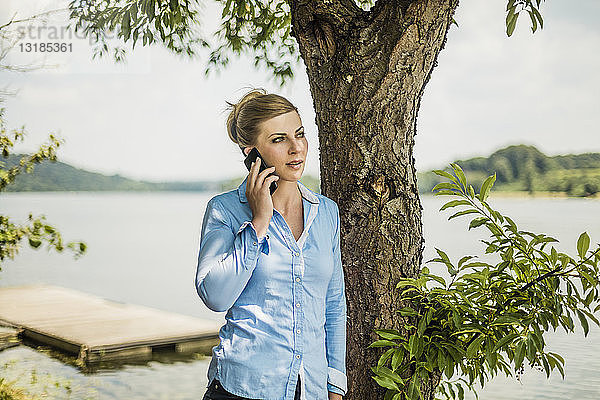 Frau mit Handy an einem See