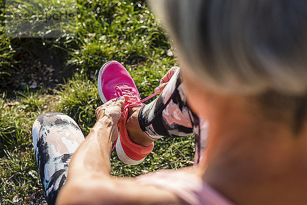 Sportliche Seniorenfrau beim Binden ihrer Schuhe