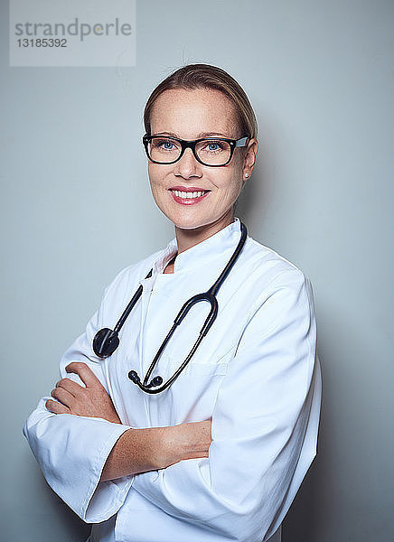 Porträt einer lächelnden Ärztin mit Stethoskop und Brille