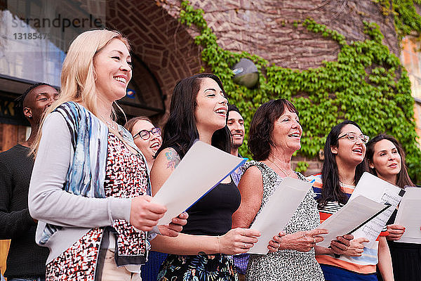 Multi-ethnische Schülerinnen und Schüler singen außerhalb der Sprachschule gemeinsam im Chor