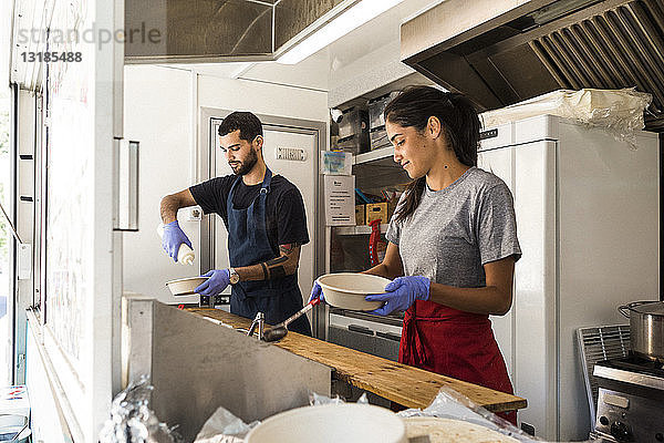 Junge multiethnische männliche und weibliche Kollegen bereiten Essen im Speisewagen zu