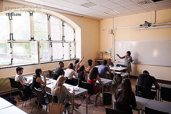 Weibliche Lehrerin stellt Fragen an Schüler in Sprachschule