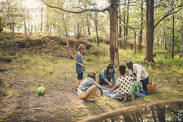 Multi-ethnische Familie genießt Picknick an Bäumen im öffentlichen Park