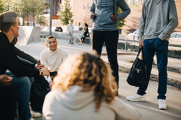 Junge männliche und weibliche Freunde unterhalten sich im Skateboard-Park