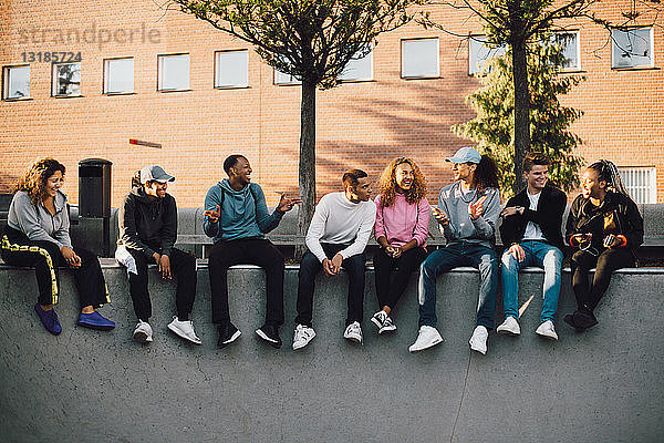 Multi-ethnische Freunde in voller Länge im Skateboard-Park sitzend