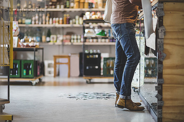 Unterer Teil des Kunden steht an der Kasse im Feinkostladen