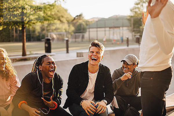 Fröhliche multi-ethnische Freunde unterhalten sich im Skateboard-Park