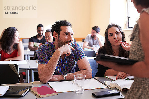 Männliche und weibliche Studenten sehen den Lehrer beim Erklären im Klassenzimmer