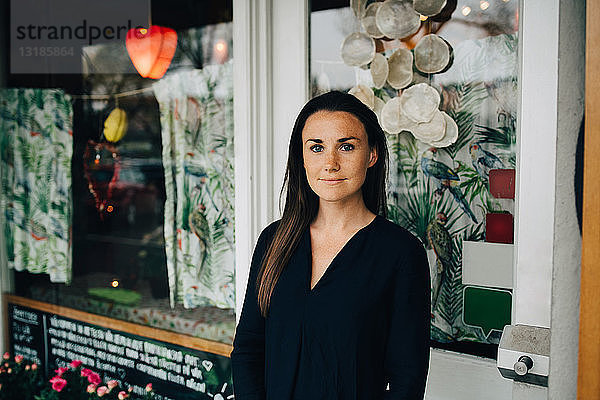 Porträt einer selbstbewussten jungen Frau  die gegen ein Restaurant steht
