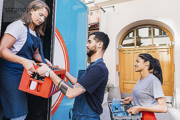 Multiethnische Kollegen halten Kisten beim Beladen von Lebensmittelwagen in der Stadt