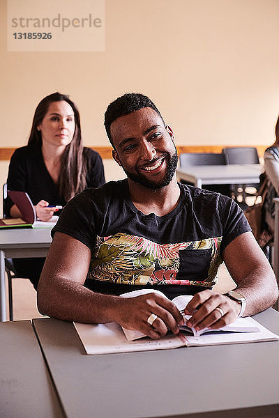 Zuversichtlicher Schüler lächelt am Schreibtisch in der Sprachschule