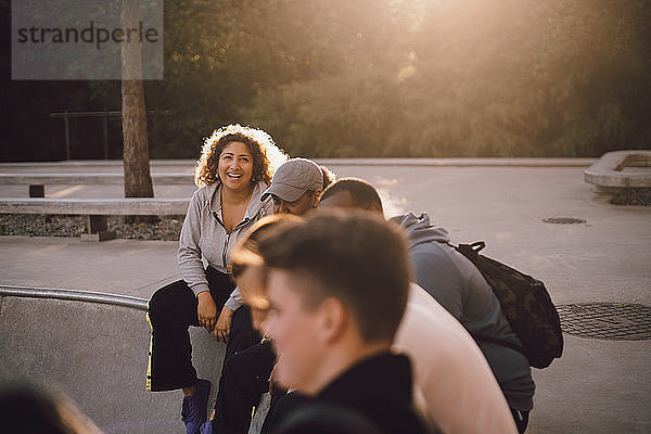 Glückliche Frau sitzt mit Freunden im Skateboard-Park