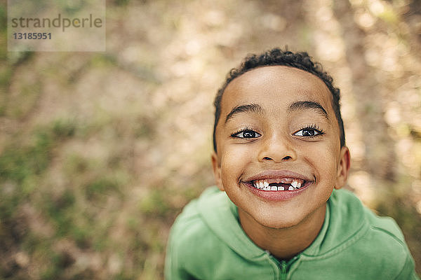 Hochwinkelaufnahme eines lächelnden Jungen mit Zahnlücke im Park