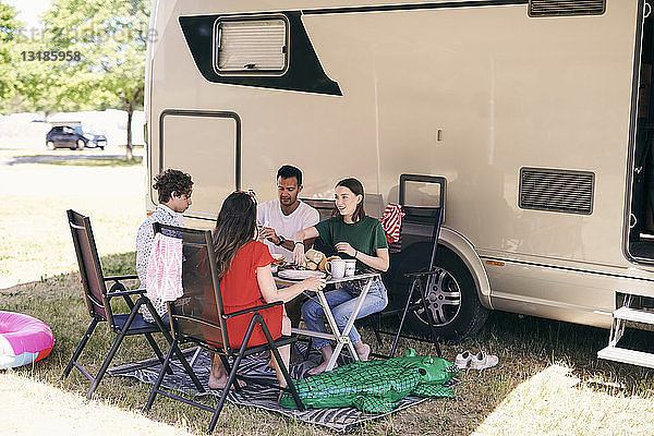 Familienmitglieder in voller Länge  die beim Zelten auf einem Wohnwagenpark Lebensmittel gegen einen Lieferwagen erhalten