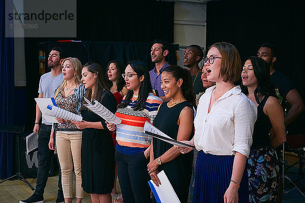 Multi-ethnische männliche und weibliche Studenten singen im Chor in der Aula