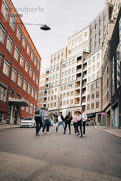 Sorgenfreie Freunde tanzen in voller Länge auf der Straße in der Stadt