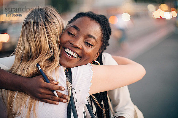Multi-ethnische Freundinnen  die sich auf der Straße in der Stadt umarmen