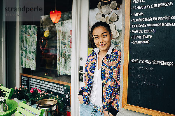 Porträt einer selbstbewussten jungen Frau  die sich im Restaurant an eine Tafel lehnt