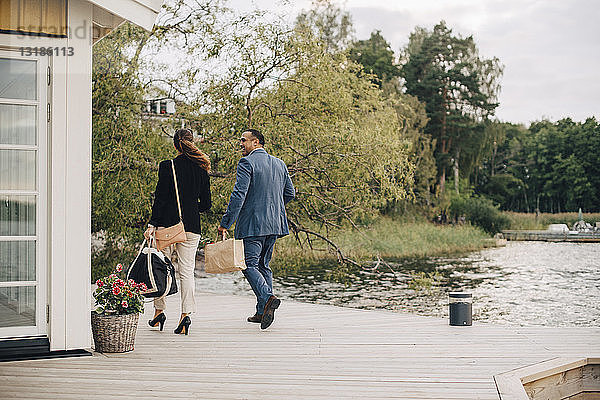 Ausgewachsenes Paar in voller Länge zu Fuß in der Ferienvilla am See