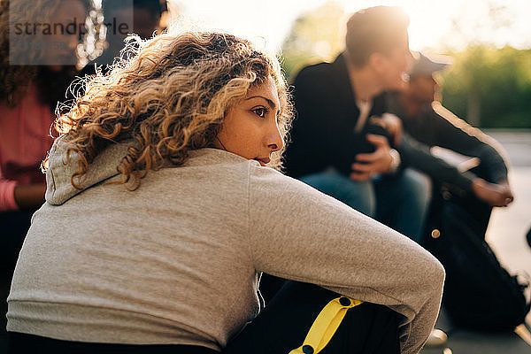 Nachdenkliche Frau sitzt mit Freunden im Skateboard-Park