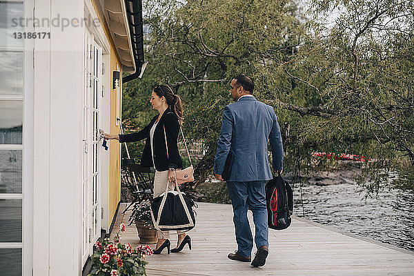 Erwachsenes Paar öffnet in voller Länge die Tür einer Ferienvilla am See