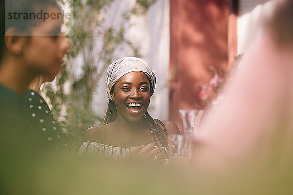Porträt einer fröhlichen jungen Frau  die bei einer Tischgartenparty sitzt