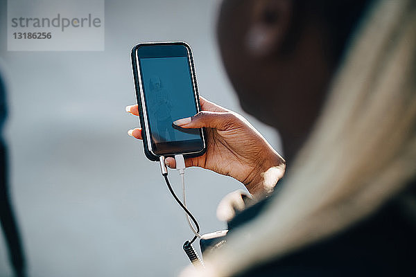 Ausgeschnittenes Bild einer Teenagerin  die über ein Smartphone Musik hört