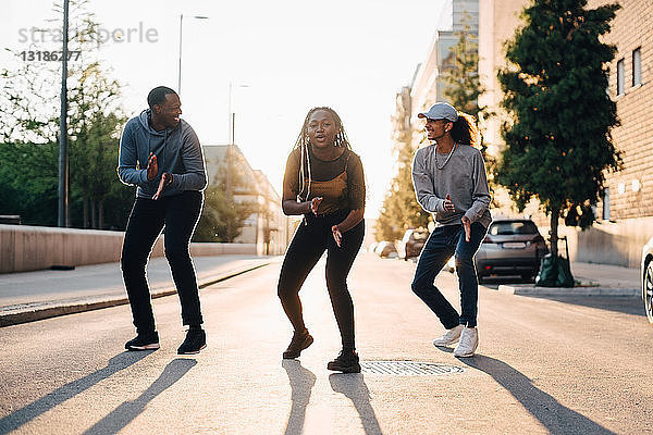 Teenager-Mädchen tanzt mit männlichen Freunden auf der Straße in der Stadt